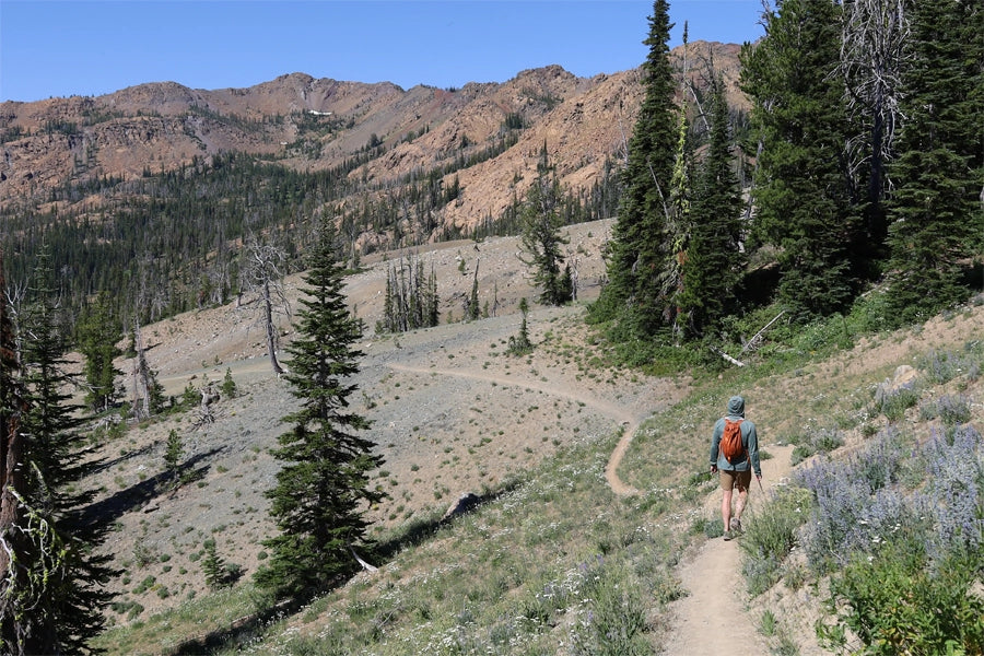 A hiker found their way down a dry, dusty hiking trail that was set between the mountains.