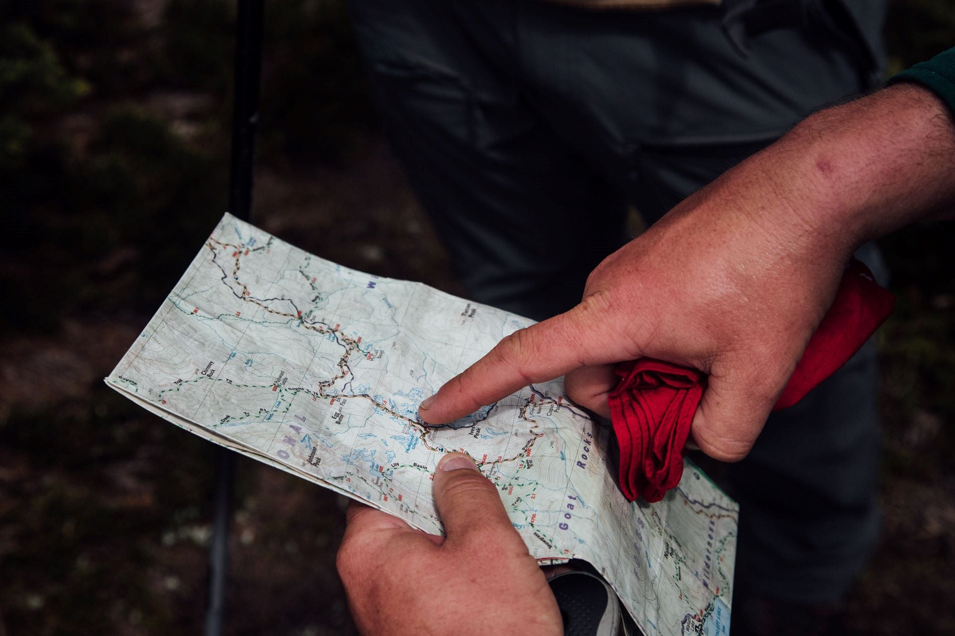 Person pointing to a trail on a map