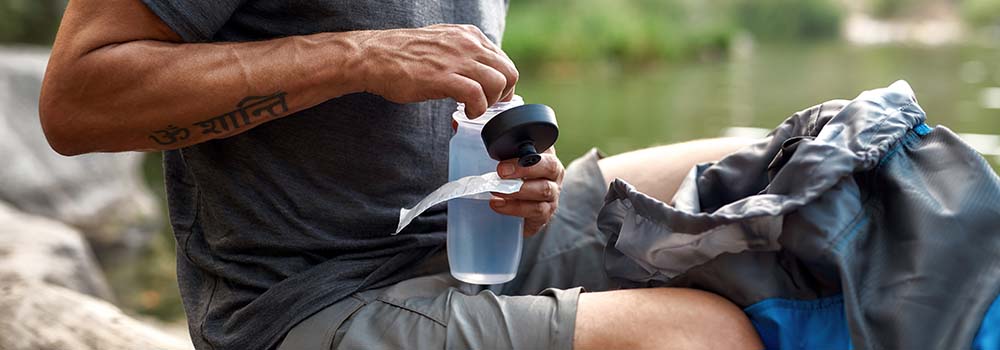 Man putting water purification tablets in his water bottle