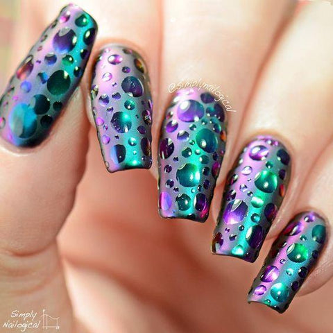 Beautifully manicured nail art with a water droplet texture and a dark shady background.