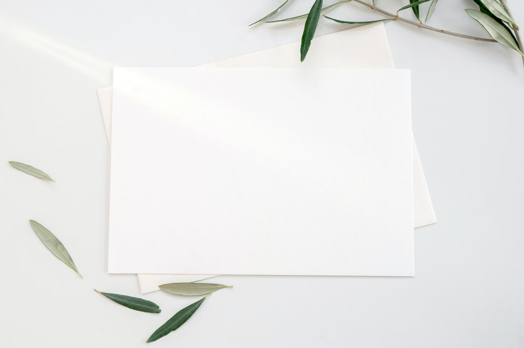 Blank textured Canson paper card on a table with leaves