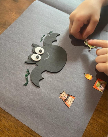 A black piece of construction paper that a child is decorating