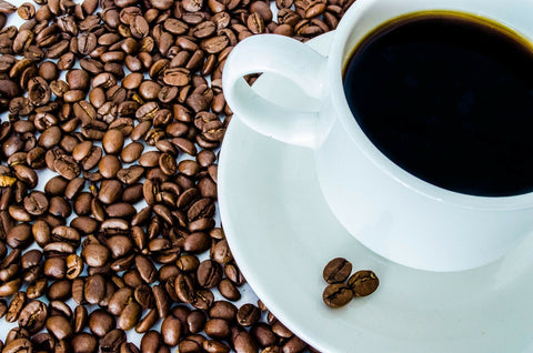 white coffee mug surrounded by coffee grounds