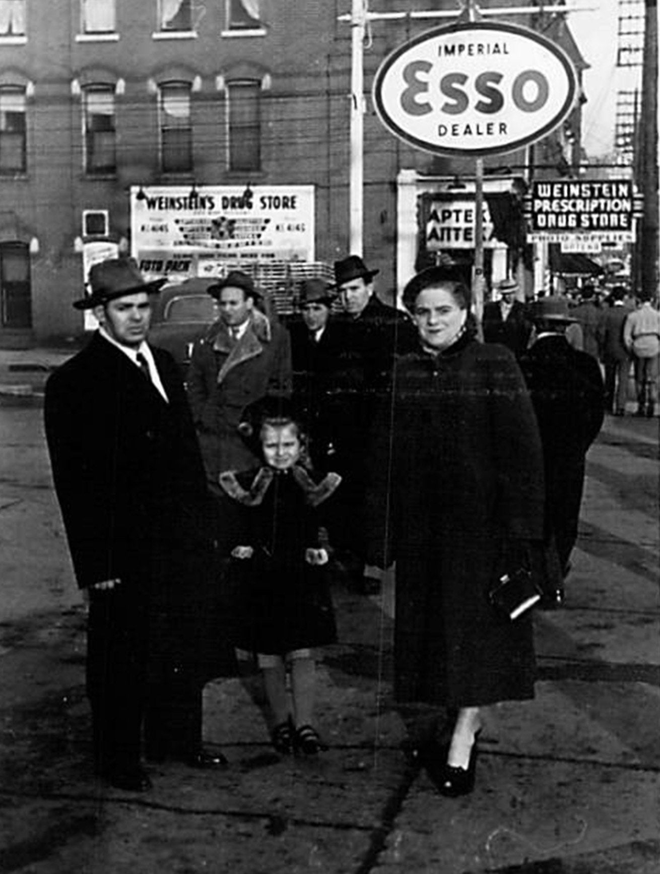 Black and white photo of men in front of gas station sign