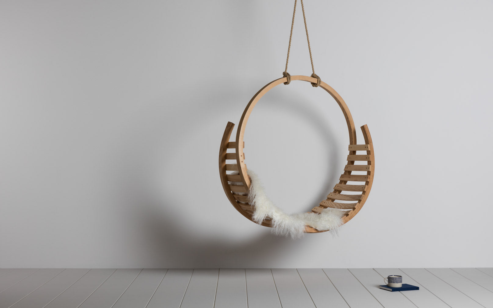 The Tom Raffield Amble Hanging Seat made of steam-bent wood.