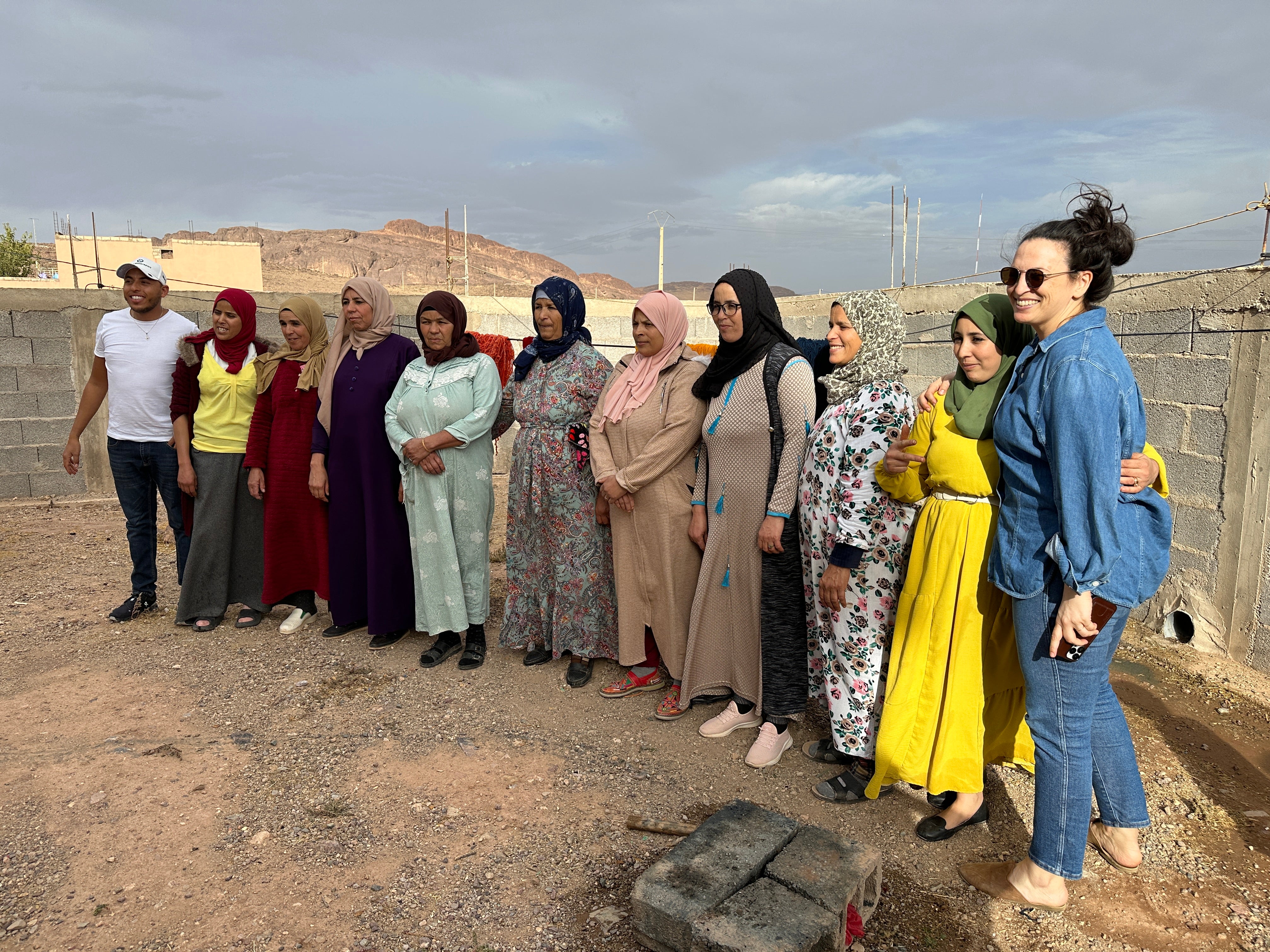 A group of women and community members stand together laughing and smiling.