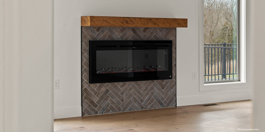 Hemme Construction inserts a Touchstone Sideline Smart Electric Fireplace into a herringbone pattern tile accent wall.