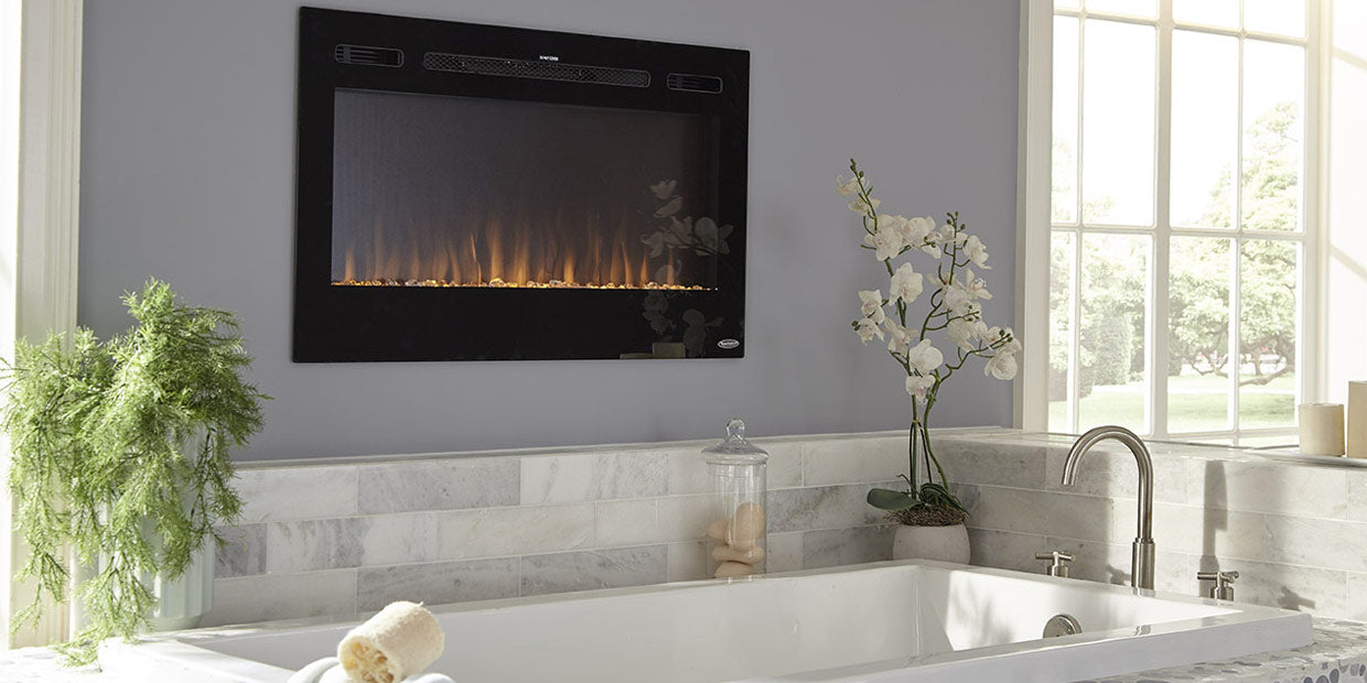 Touchstone Sideline 36 Electric Fireplace recessed in bathroom wall, showing orange flames and crystal flame base