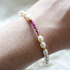 Marie Nicole Bijoux - Woman's wrist wearing a pearl and ruby bracelet