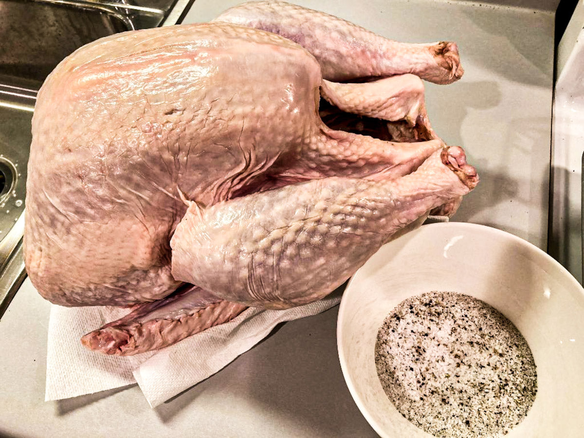 Photo of raw turkey next to bowl of salt and pepper