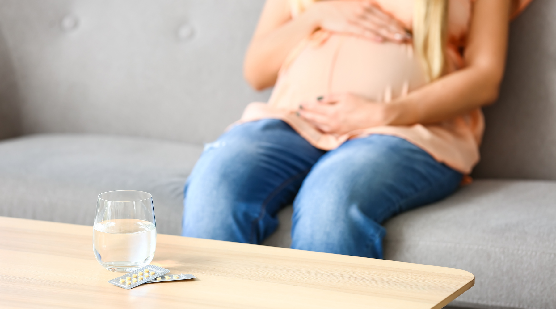 pregnant woman sitting with pills on table