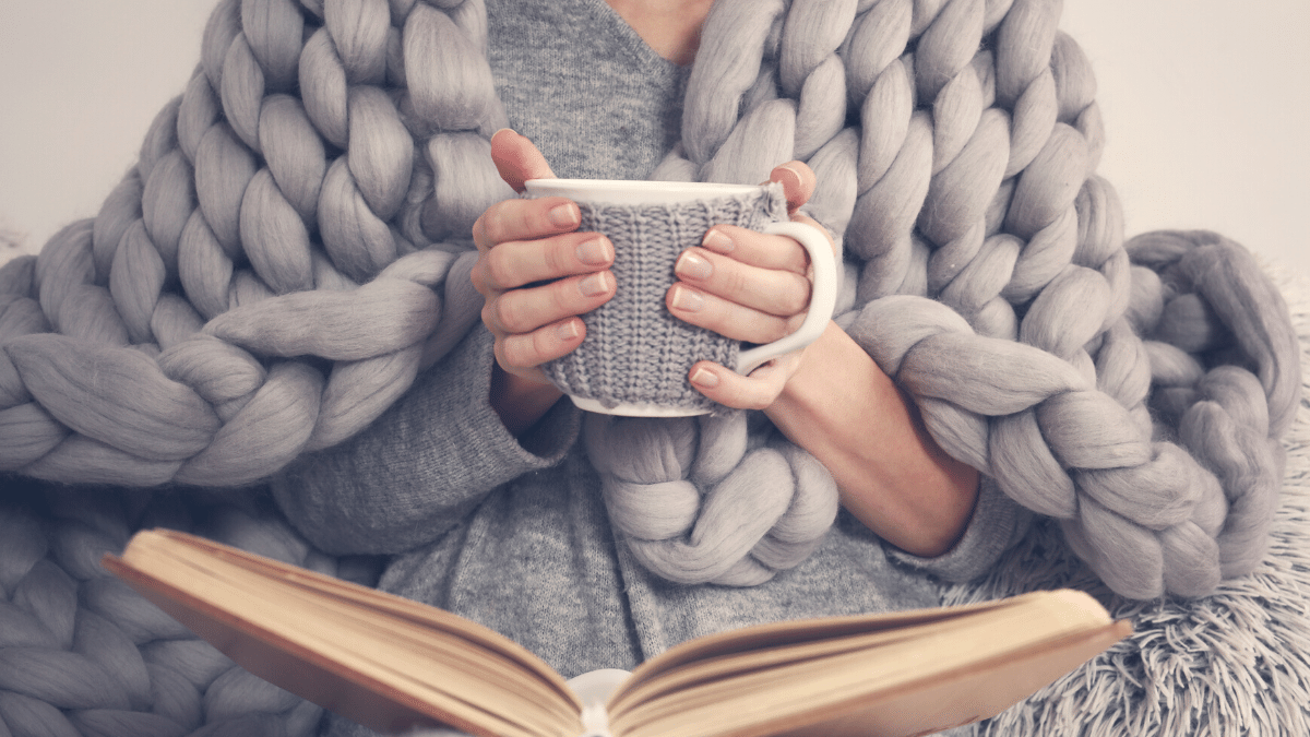woman with blanket, book and cup of tea
