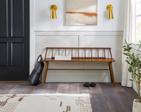 Solid wood brown spindle bench with gold sconces and a painting in the background