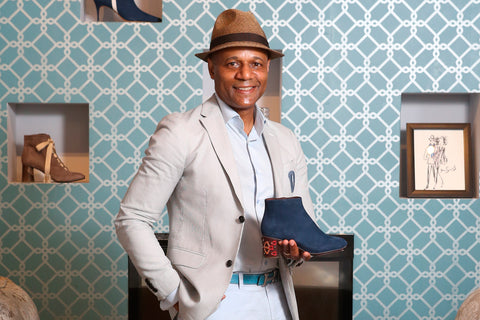 Derrick Adams, co-owner of Studio D Shoes, a shoe boutique in North Toronto stands in his store holding a blue boot