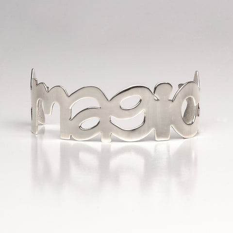 Sterling silver cuff bracelet in the shape of the word magic with a stars on either side.