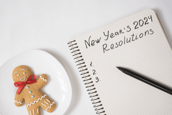 A blank list of New Year Resolution for 2024 beside a Gingerman bread on a plate.