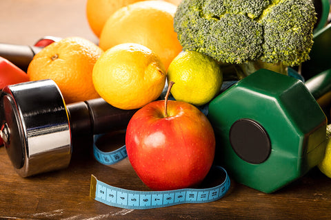 Fruits and vegetables with a set of dumbbells and a measuring tape