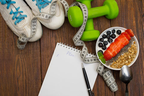 A table with food, a fitness planner and exercise tools
