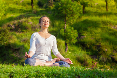 A woman in white meditating with nature.