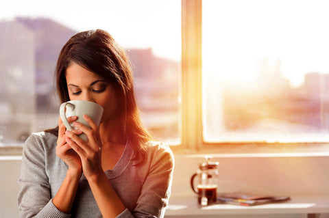 A woman enjoying her cup of coffee.