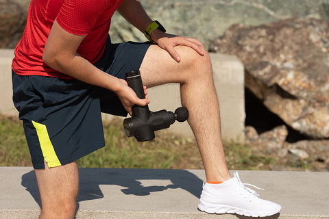 A man in sports gear uses massage gun to relax his muscles