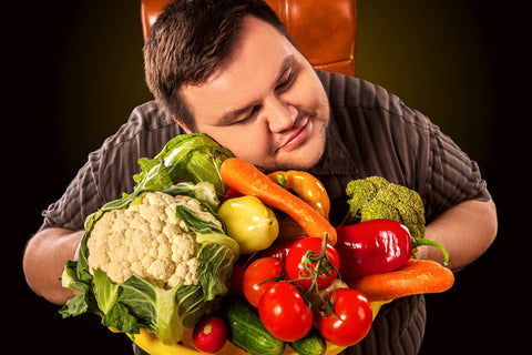 An obese man embraces a bunch of vegetables