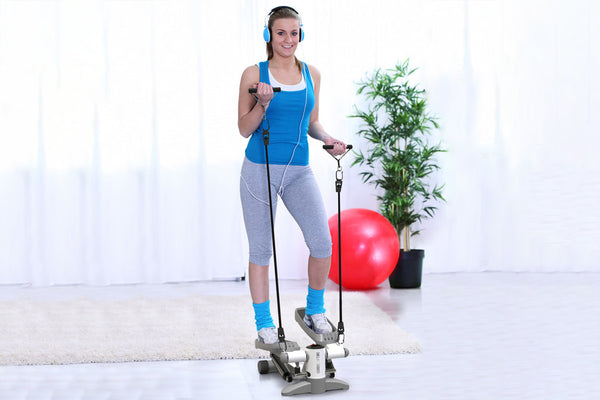 A woman in blue sportswear exercises using a mini stepper