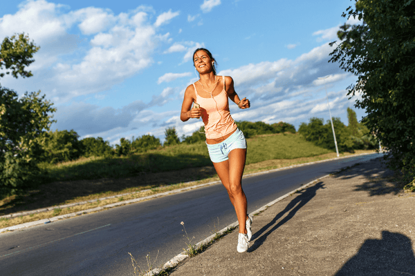 A Woman Wearing A Fitness Attire Running On The Side Of The Road