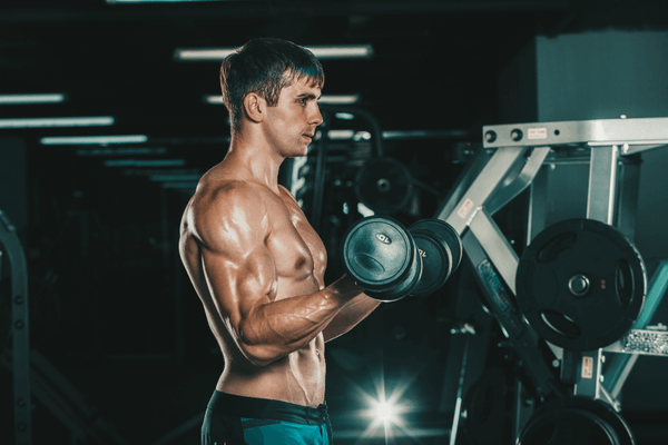 A Toned Muscle Man In A Gym Lifting A Dumbbell