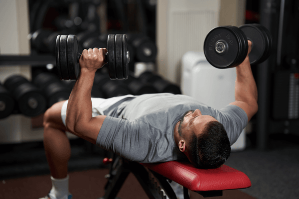 A Man Performing A Bench Press Exercise With Two Dumbbells, Focusing On His Upper Body Strength