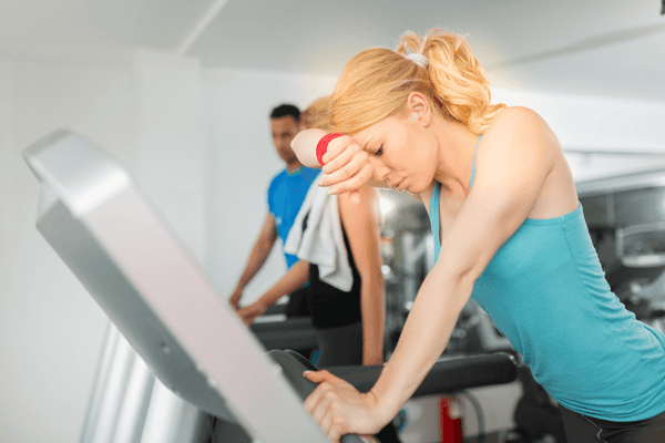 A blonde woman in blue sportswear looking exhausted while working out.