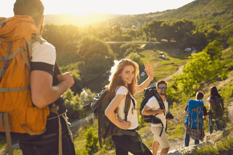 A Woman Waving With Her Friends In The Background Hiking Together In A Mountain