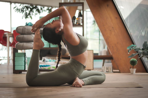 A woman in grey sportswear performs a yoga pose