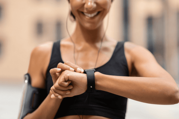 A woman in black sportswear using her smartwatch in her fitness routine.