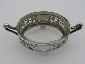 Pair of German silver salts, oval in shape, each with two handles and clear liners. Each is decorated with a pierced panel of griffins and blank cartouches. Each have four ball feet. Circa 1910.