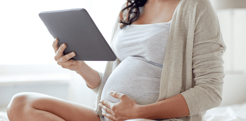 cut off image of a pregnant woman holding a digital tablet 