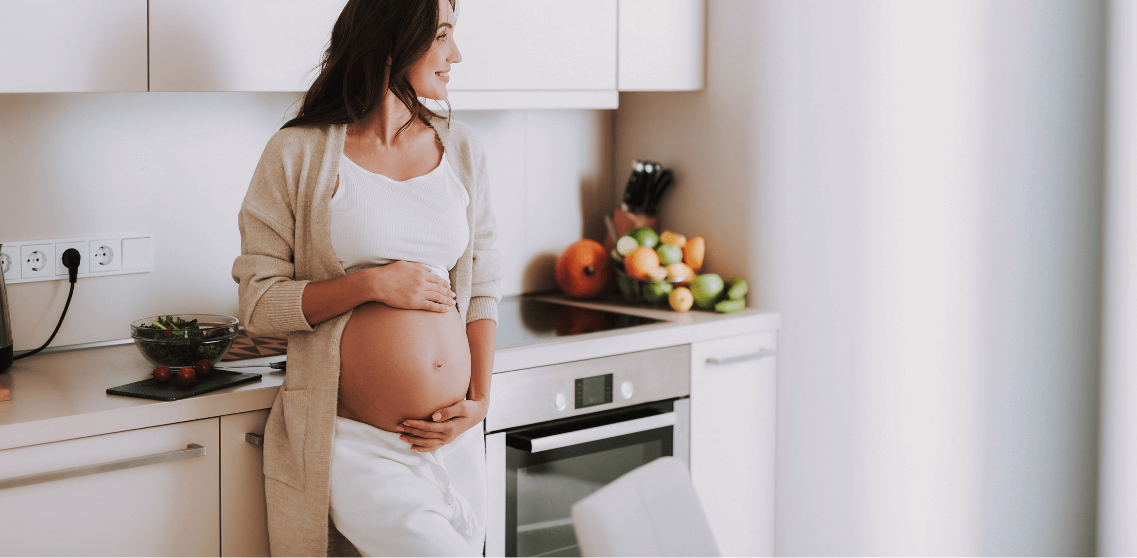 woman holding her bump in the kitchen smiling