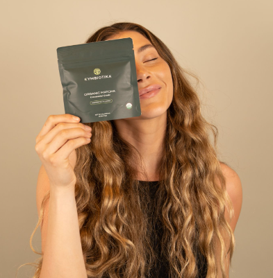 Model smiling with Cymbiotika Matcha packet