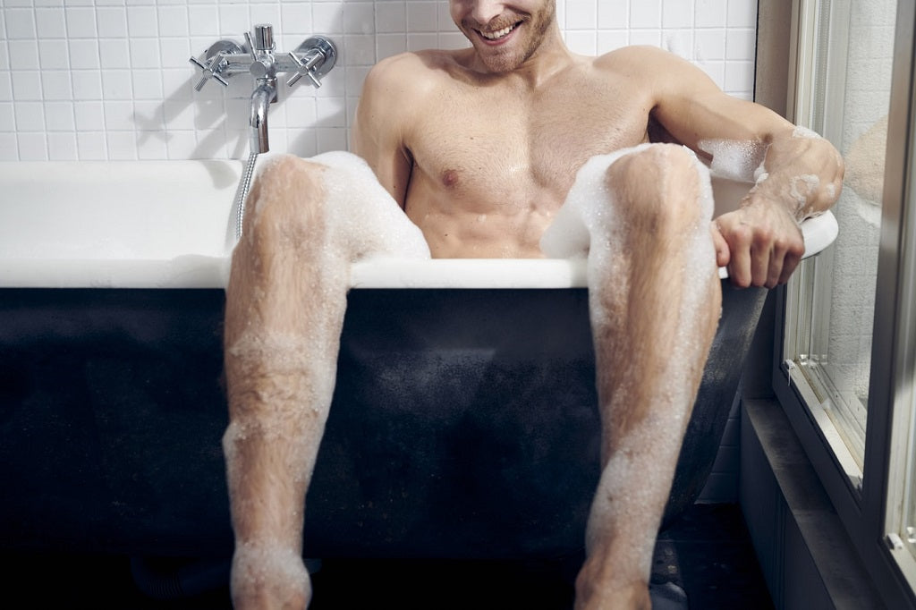 Naked man washing in a bath tub