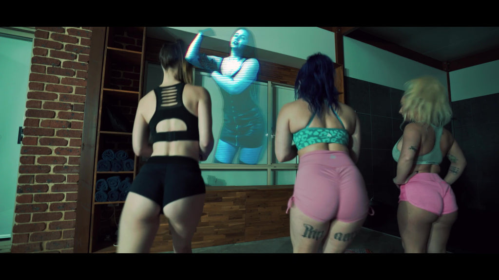 Three women in gym clothing with a hologram of Natasha Zare in front of them.