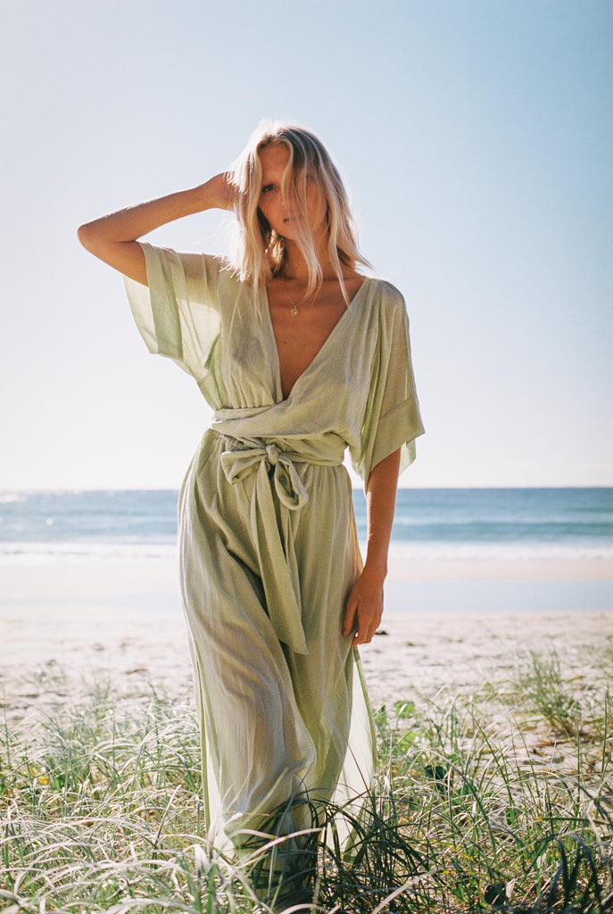 Woman wearing mint green maxi dress modeling on a grass field near the shoreline