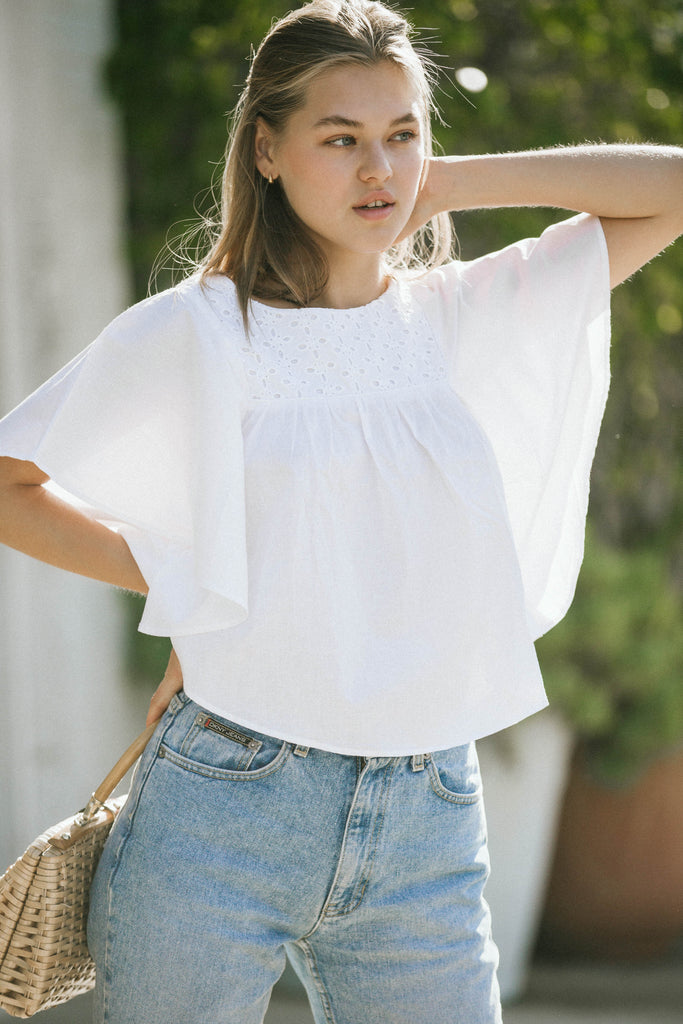 our model wearing white top and jeans holding a rustic rattan bag while her arms up