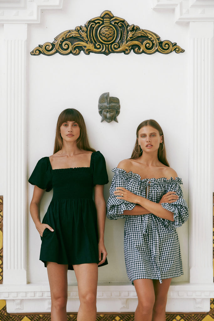 Two women wearing Hazel & Folk dresses standing next to each other in front of a white wall