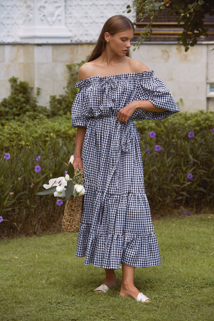 A woman on front yard wearing Emmaline Gown in Black Gingham dress