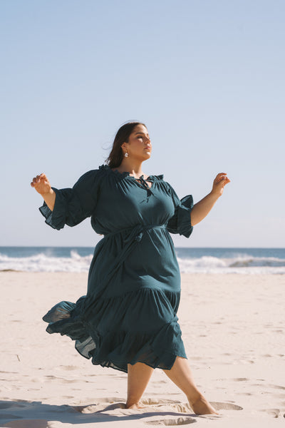 Plus size women standing a beach wearing a teal hazel and folk dress