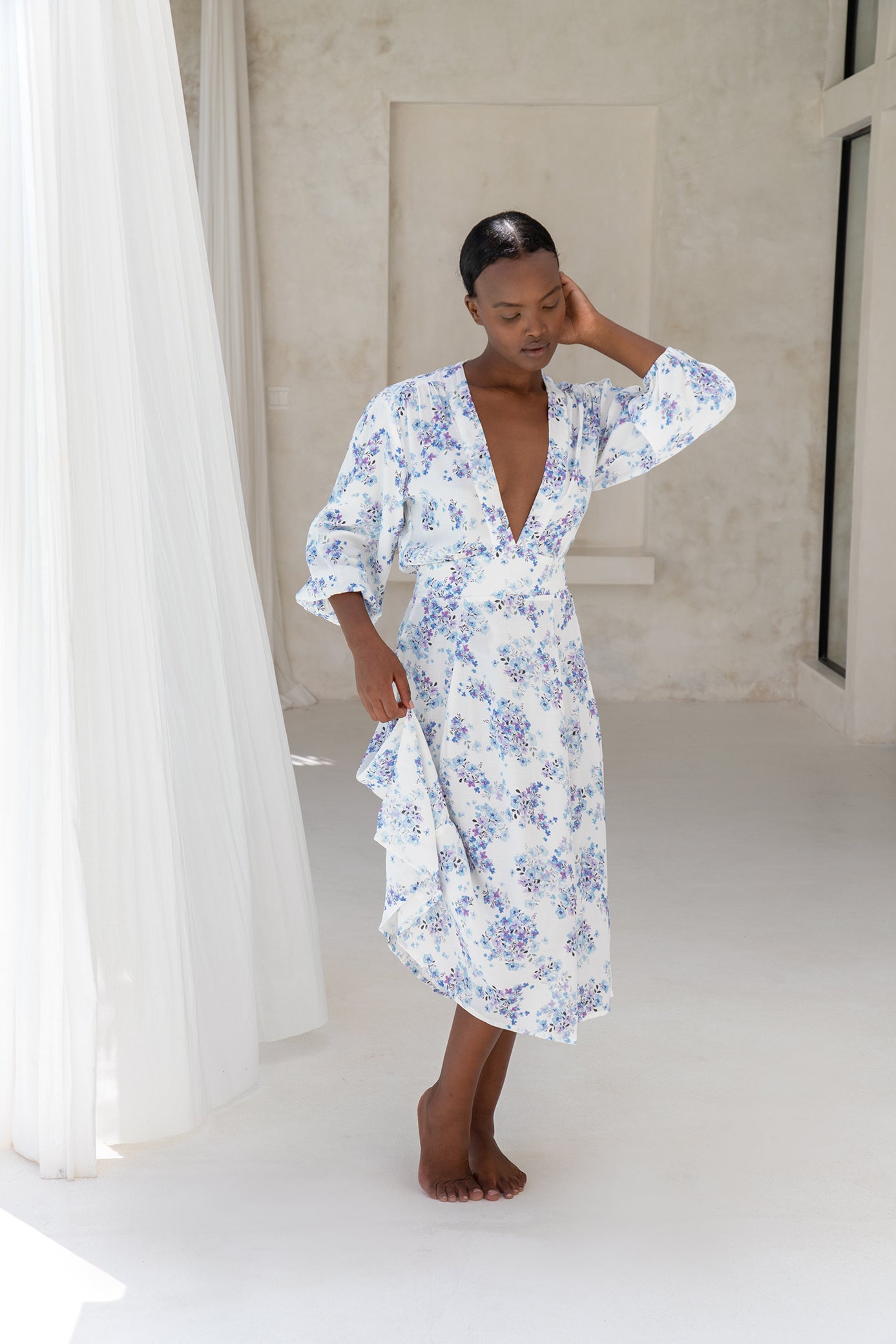 Woman with short black hair wearing white wrap dress