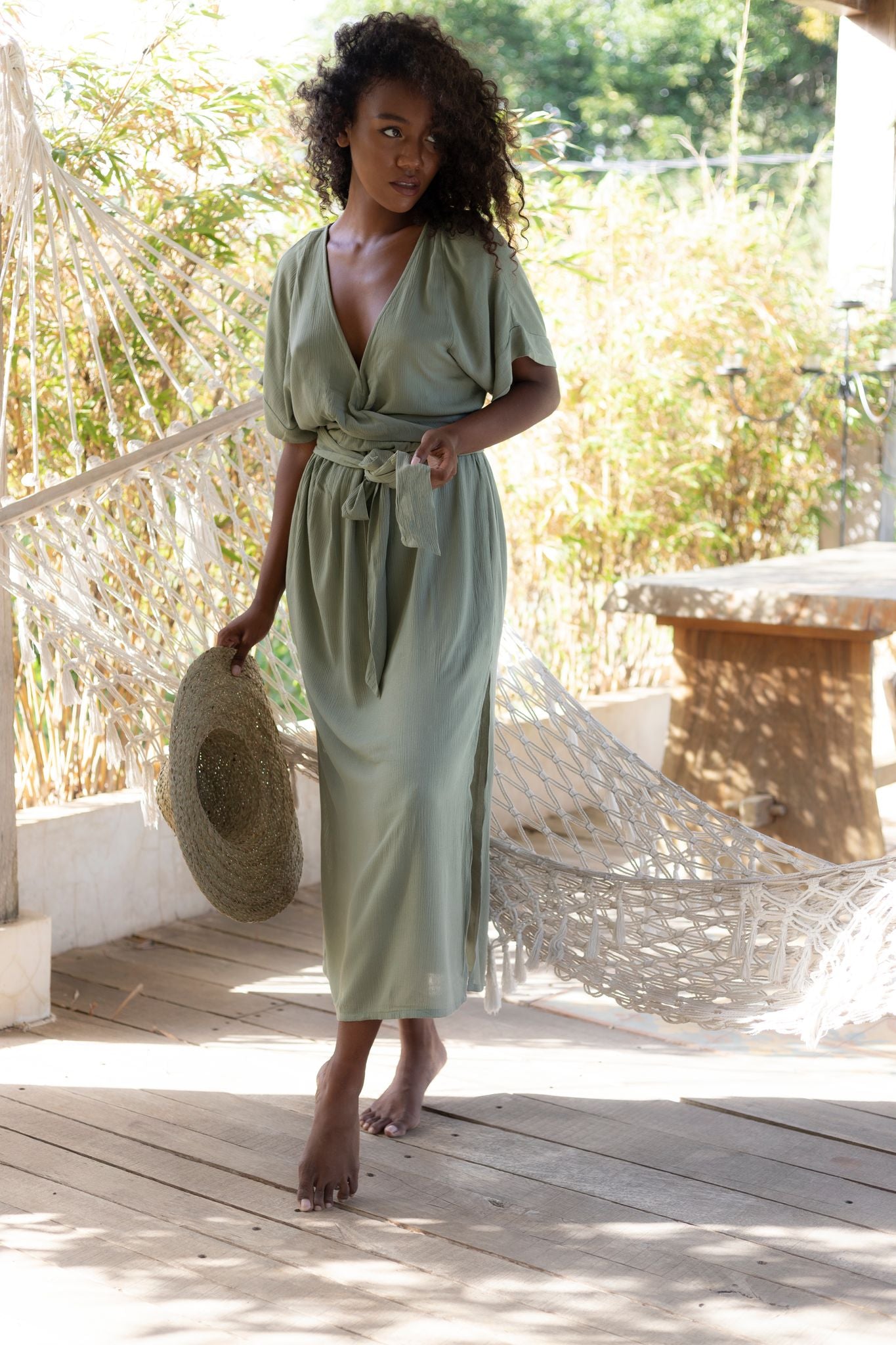 Woman with dark hair wearing sustainably made sage green maxi dress