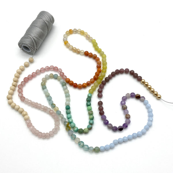 beaded gemstones in a rainbow of colors on spool of grey thread