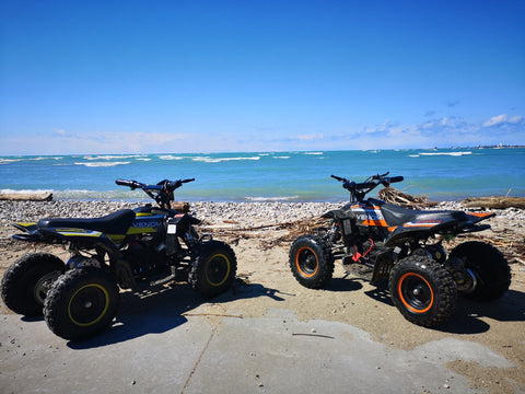 Venom Motorsports electric ATV riding at the beach in orange and yellow