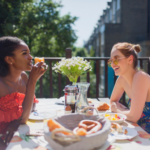 2 female friends having brunch together, laughing and enjoying each other's company
